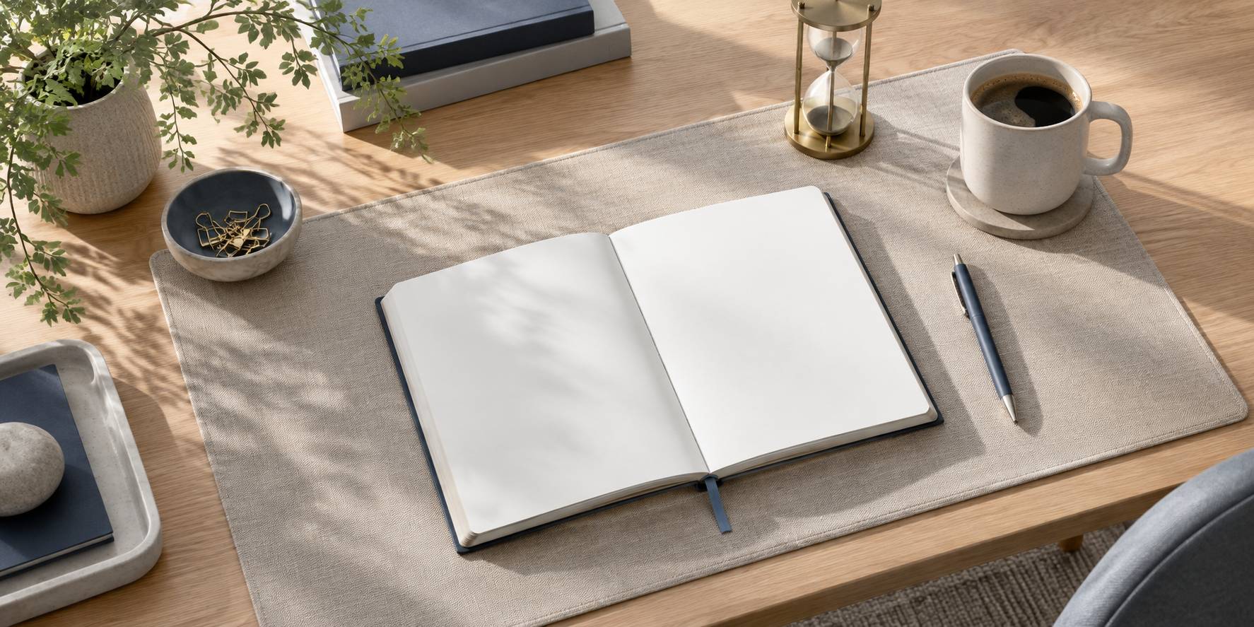 Agenda vierge, stylo, sablier et tasse sur un bureau épuré